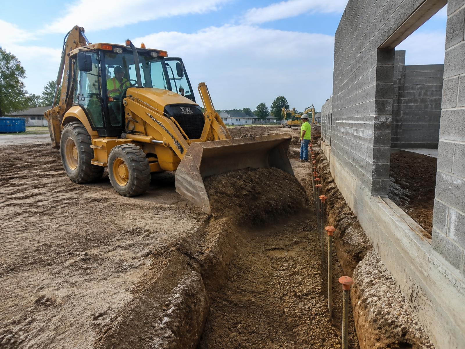 Backhoe loader backfilling a foundation trench